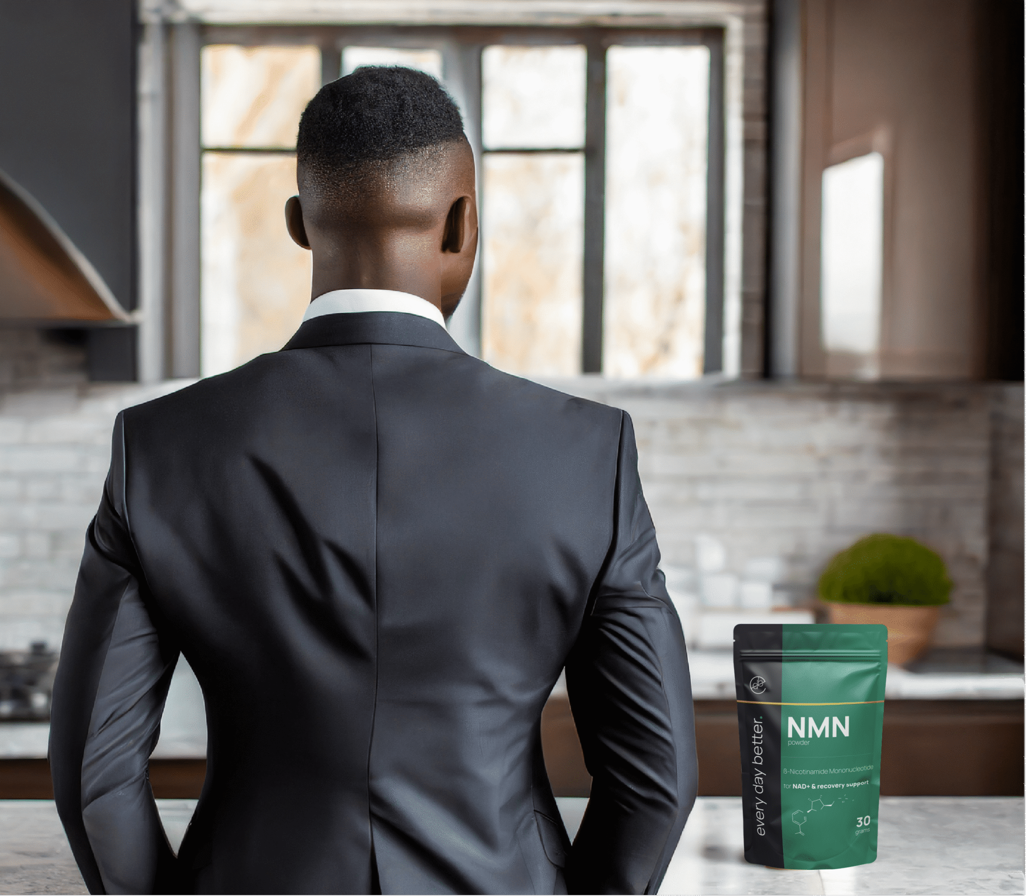 Career and energy: NMN, TMG, and GlyNAC explained Zakenman in zwart pak van achteren gezien in een moderne keuken met een groen zakje Every Day Better NMN poeder op het aanrecht